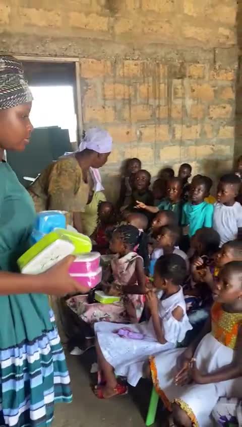 A team member giving out lunch boxes in a classroom
